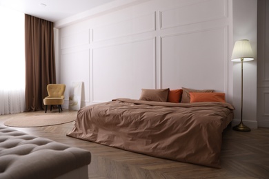 Bed with orange and brown linens in stylish room