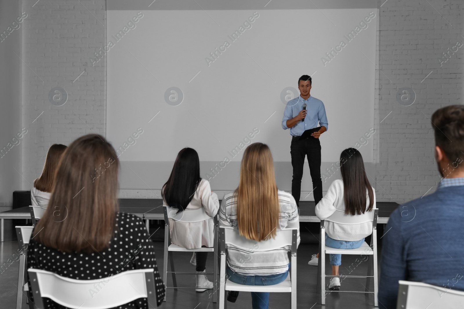 Photo of Male business trainer giving lecture in conference room with projection screen