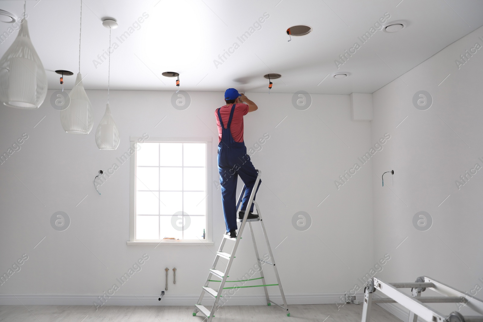 Photo of Worker installing stretch ceiling in empty room