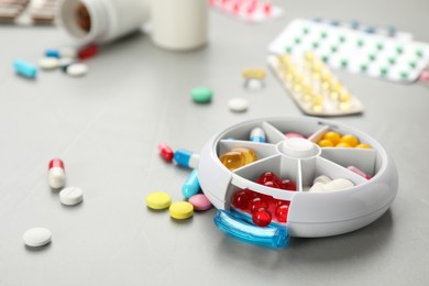 Plastic box with different pills on light grey stone table