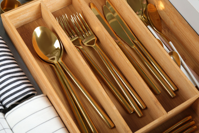 Photo of Open drawer with different utensils and folded towels, closeup. Order in kitchen