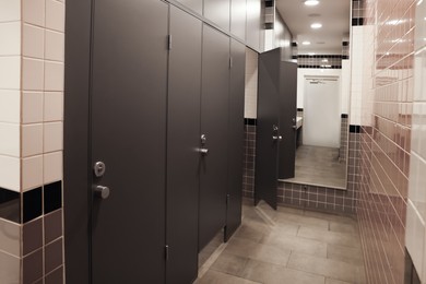 Photo of Public toilet interior with stalls and tiled walls