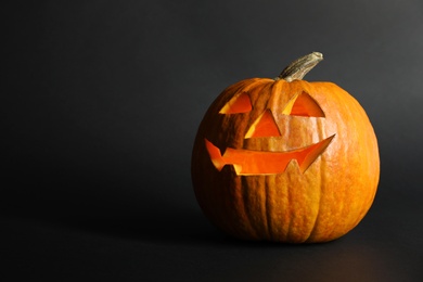 Photo of Halloween pumpkin head jack lantern on dark background with space for text