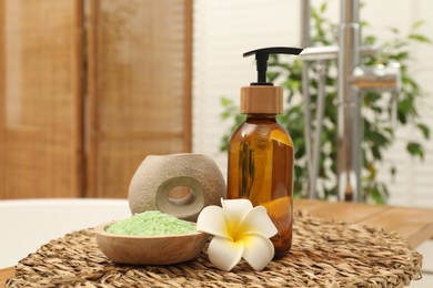 Different spa products and beautiful flower on tub tray in bathroom