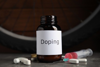 Photo of Pills, syringe and bike wheel on grey table. Using doping in cycling sport concept