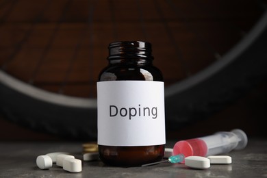 Pills, syringe and bike wheel on grey table. Using doping in cycling sport concept