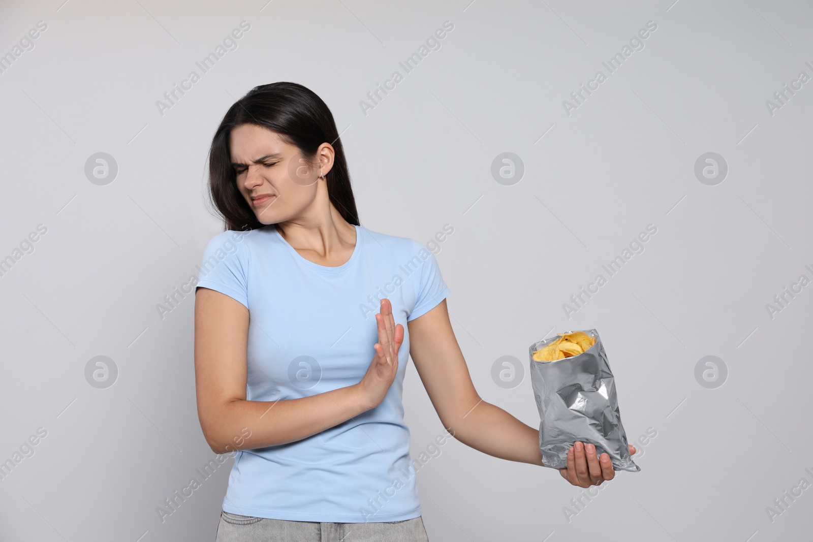 Photo of Beautiful woman refusing to eat potato chips on grey background