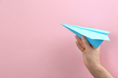 Woman holding paper plane on pink background, closeup. Space for text