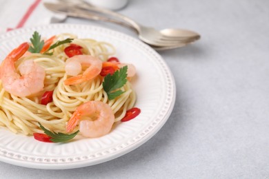 Photo of Tasty spaghetti with shrimps, chili pepper and parsley on grey table, closeup. Space for text