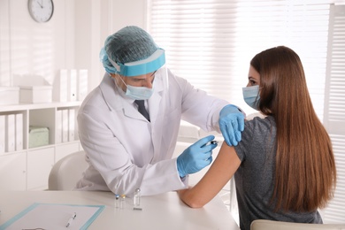 Doctor vaccinating young woman against Covid-19 in clinic