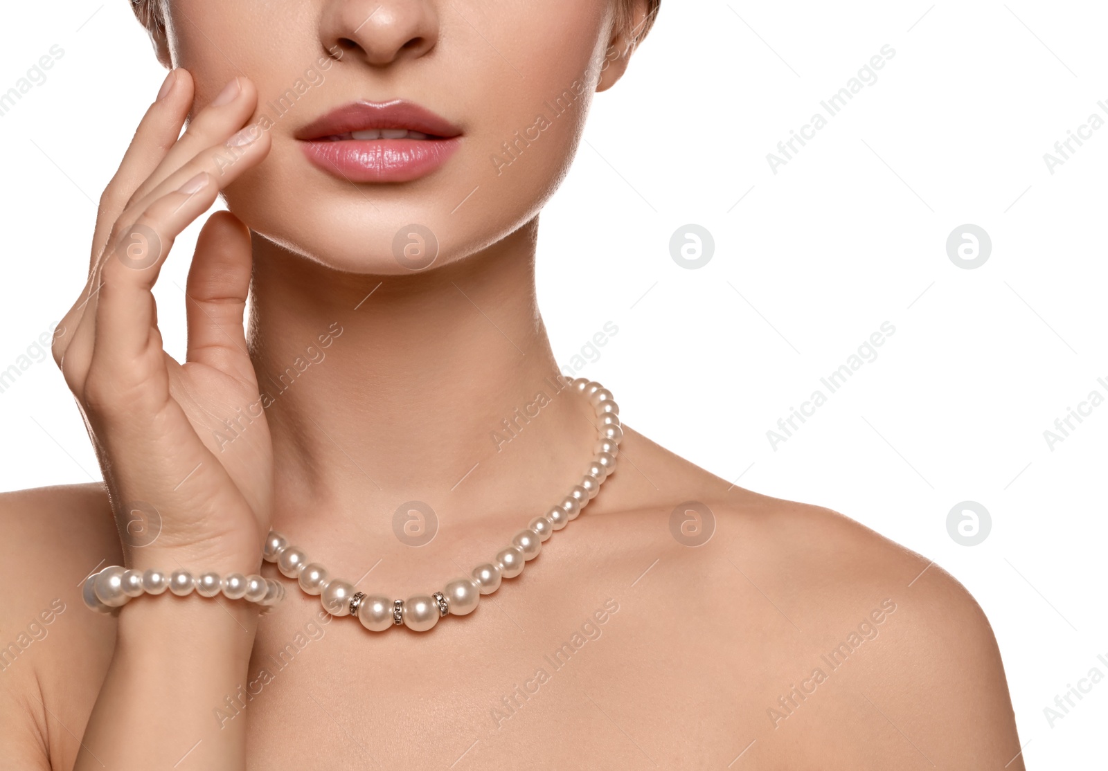 Photo of Young woman wearing elegant pearl jewelry on white background, closeup