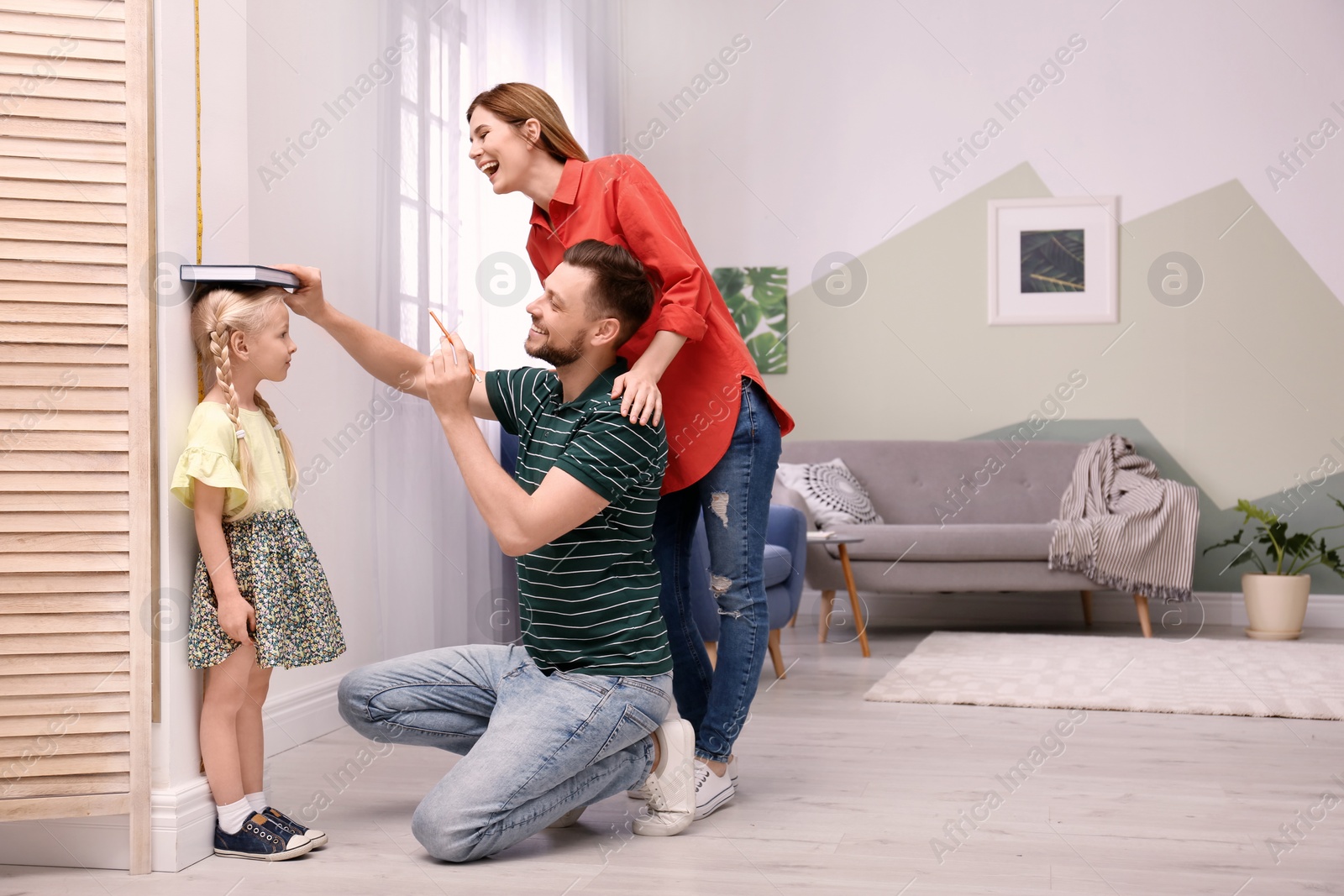 Photo of Parents measuring their daughter's height at home