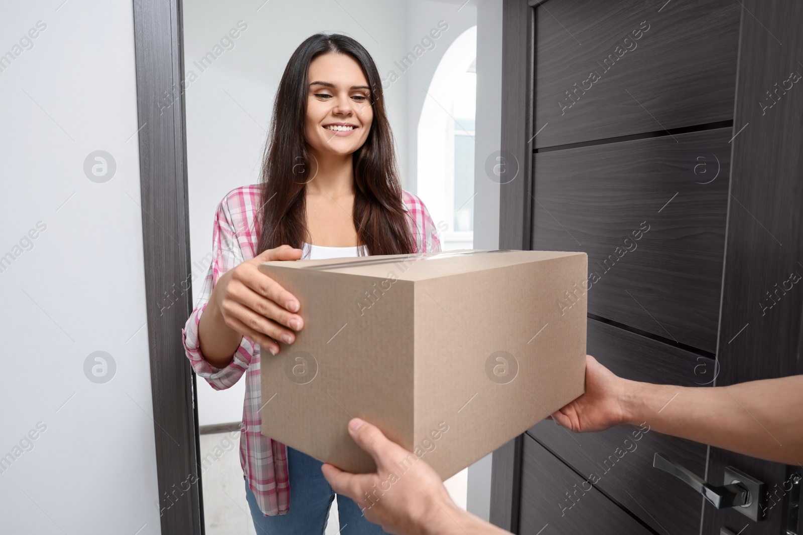 Photo of Woman receiving parcel from courier at home, closeup