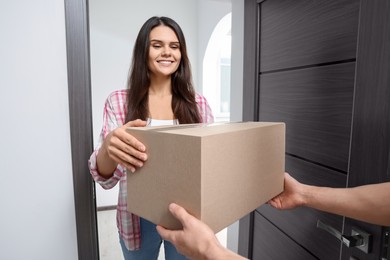 Woman receiving parcel from courier at home, closeup