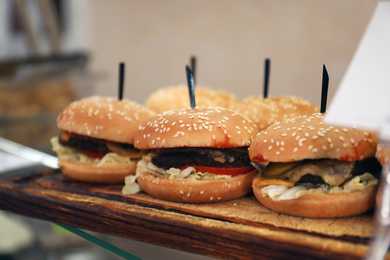 Photo of Tasty burgers on wooden board in school canteen. Fresh food