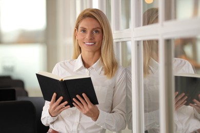 Smiling woman with book in office. Lawyer, businesswoman, accountant or manager