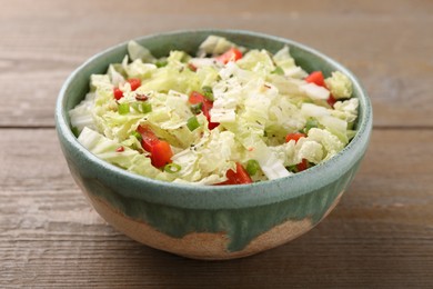 Photo of Tasty salad with Chinese cabbage, bell pepper and green onion in bowl on wooden table, closeup