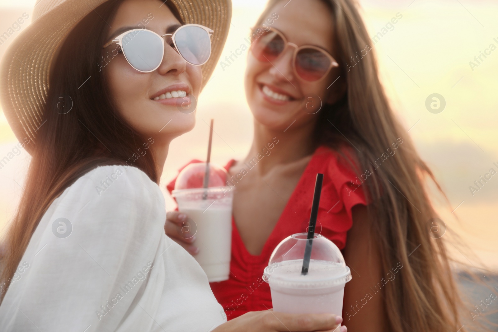 Photo of Beautiful young women with tasty milk shakes on beach