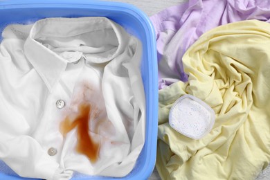 Photo of Garment and powdered detergent near basin with white shirt, top view. Hand washing laundry