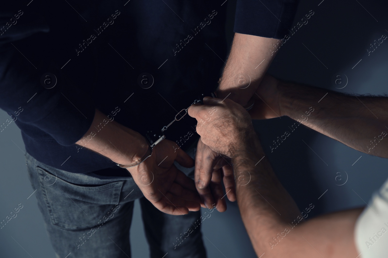 Photo of Man putting handcuffs on drug dealer, closeup view