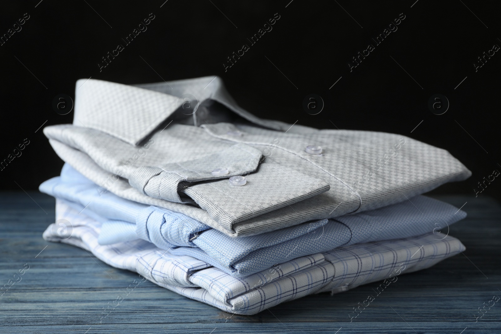 Photo of Stack of classic shirts on blue wooden table