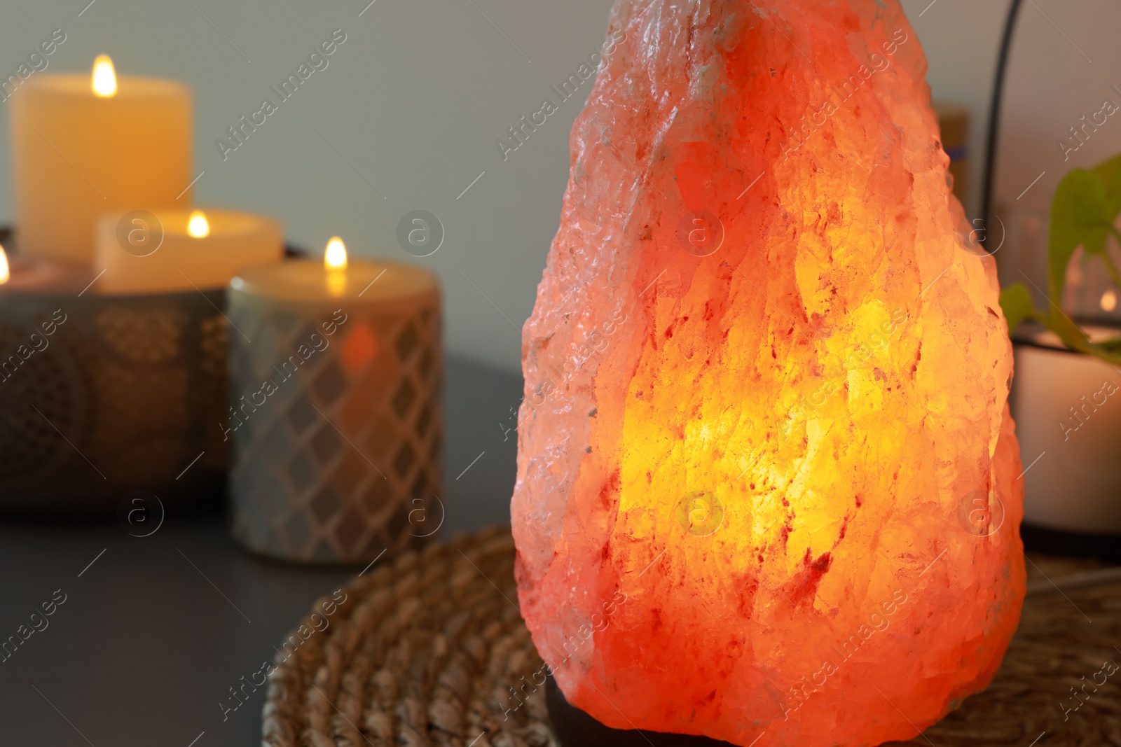 Photo of Himalayan salt lamp and candles on table, closeup