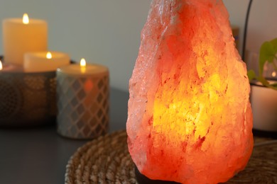 Himalayan salt lamp and candles on table, closeup