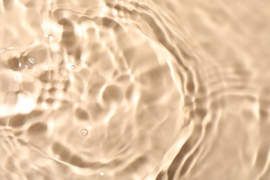 Photo of Closeup view of water with rippled surface on beige background