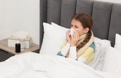 Sick girl with tissue coughing on bed at home