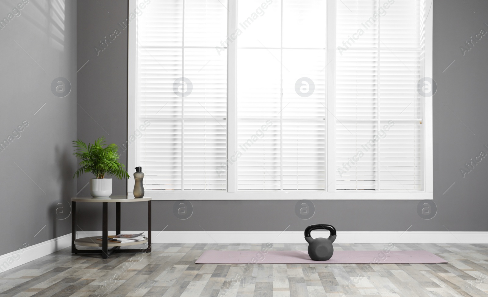 Photo of Exercise mat with kettlebell near table in spacious room