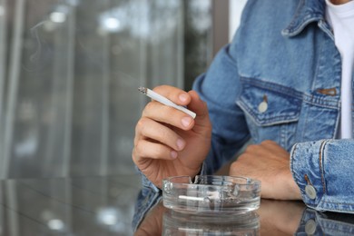 Photo of Man smoking cigarette at table in outdoor cafe, closeup