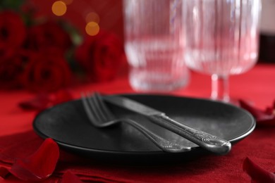 Photo of Place setting with roses on red table, closeup. Romantic dinner