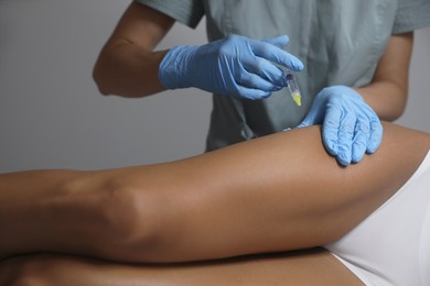 Photo of Young woman getting legs injection in salon, closeup