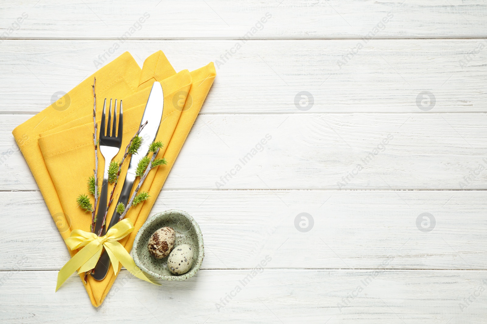 Photo of Cutlery set and beautiful willow branches on white wooden table, flat lay with space for text. Easter celebration