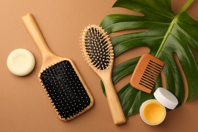 Photo of Flat lay composition with wooden hairbrushes and cosmetic products on light brown background