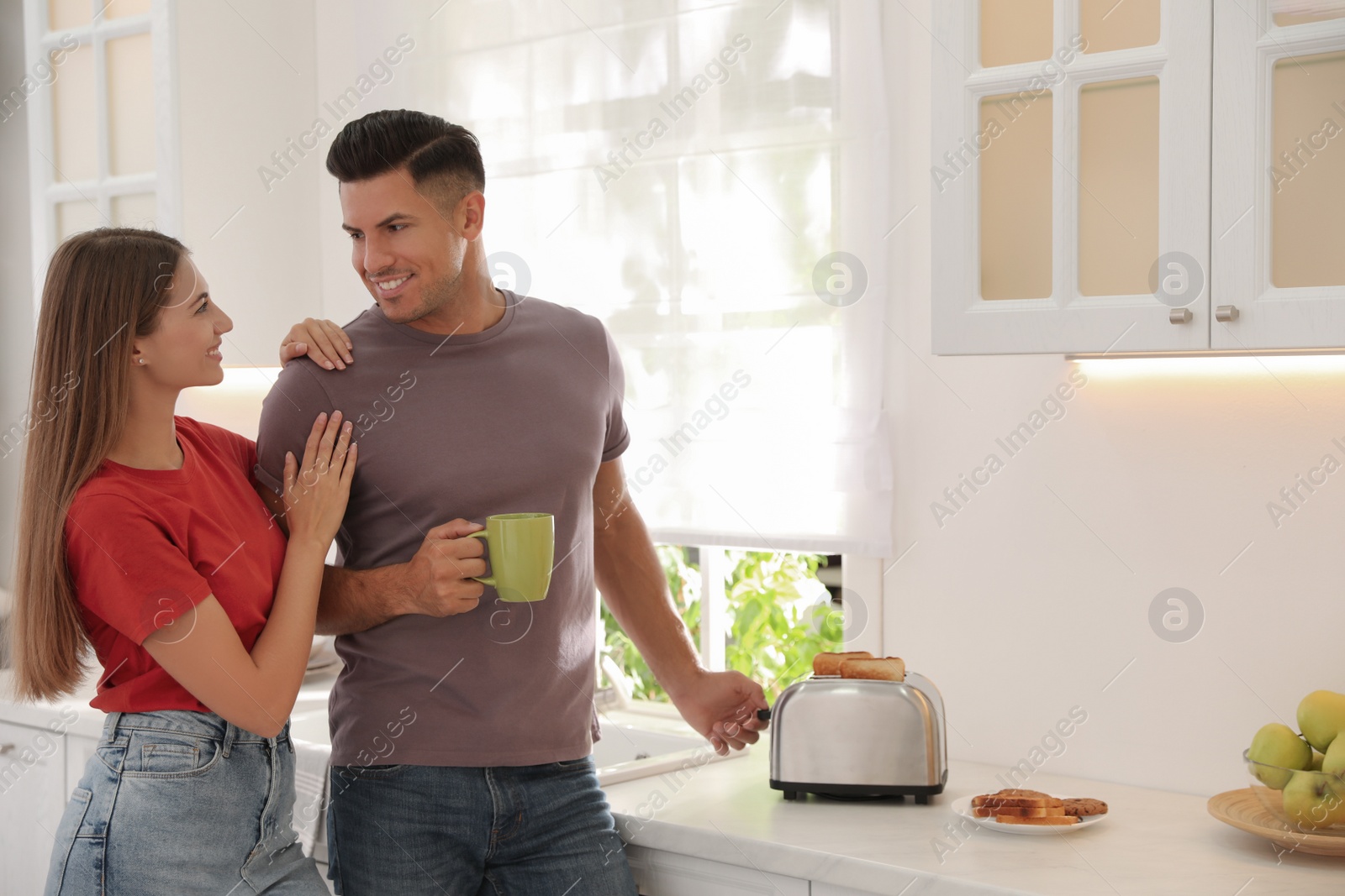 Photo of Happy couple preparing breakfast with toasted bread in kitchen