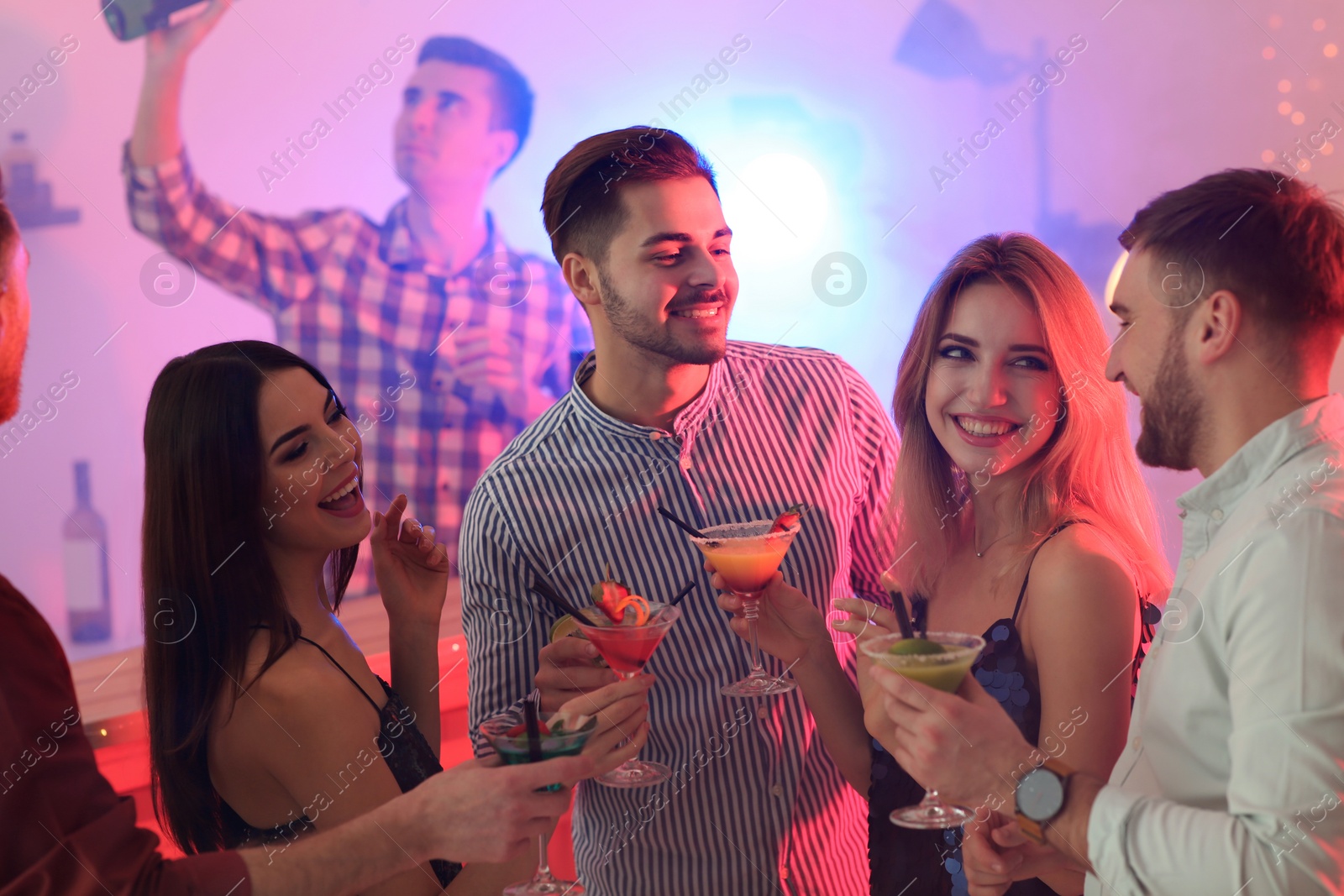 Photo of Group of young people holding martini cocktails at party