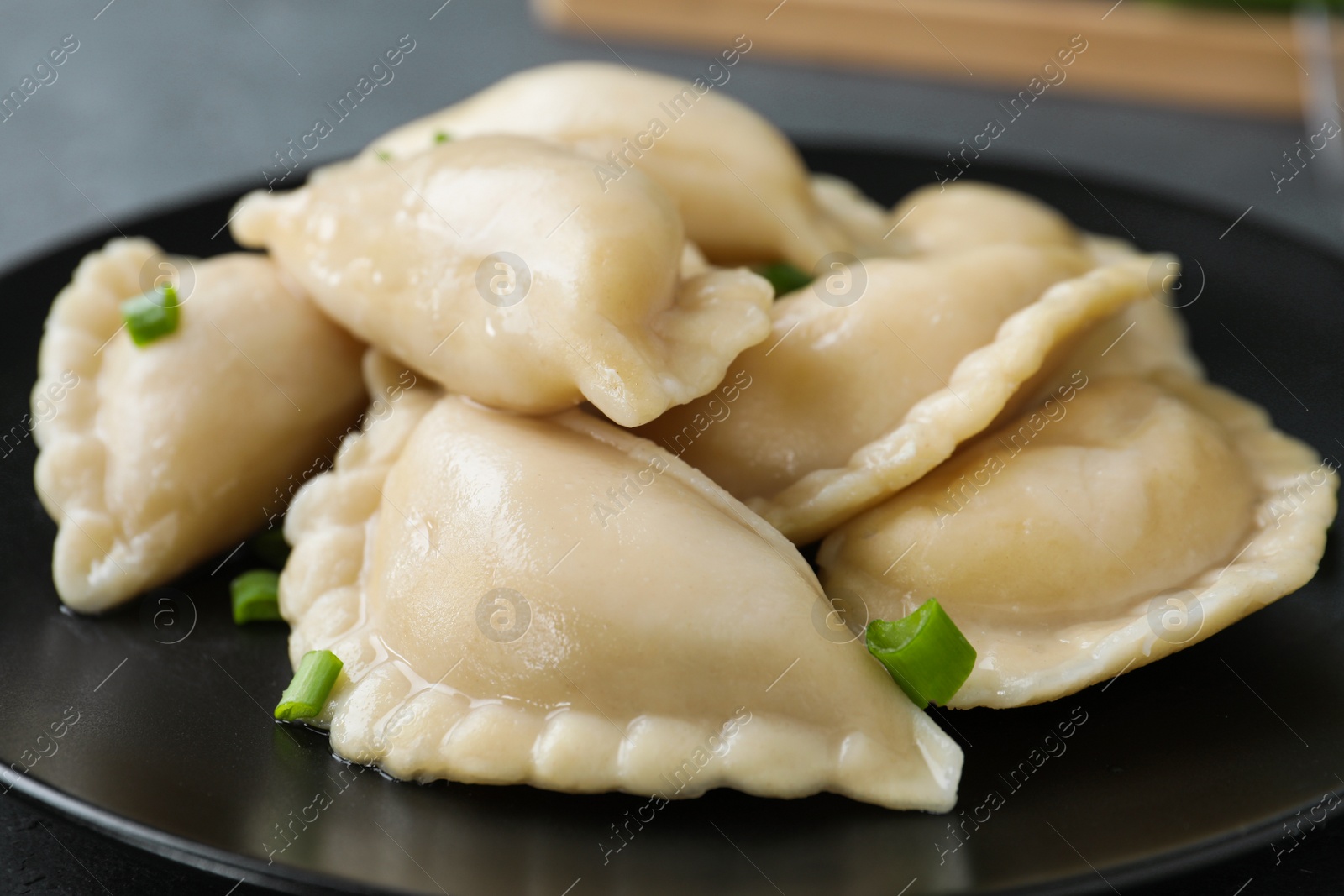Photo of Tasty dumplings served with green onion on plate, closeup