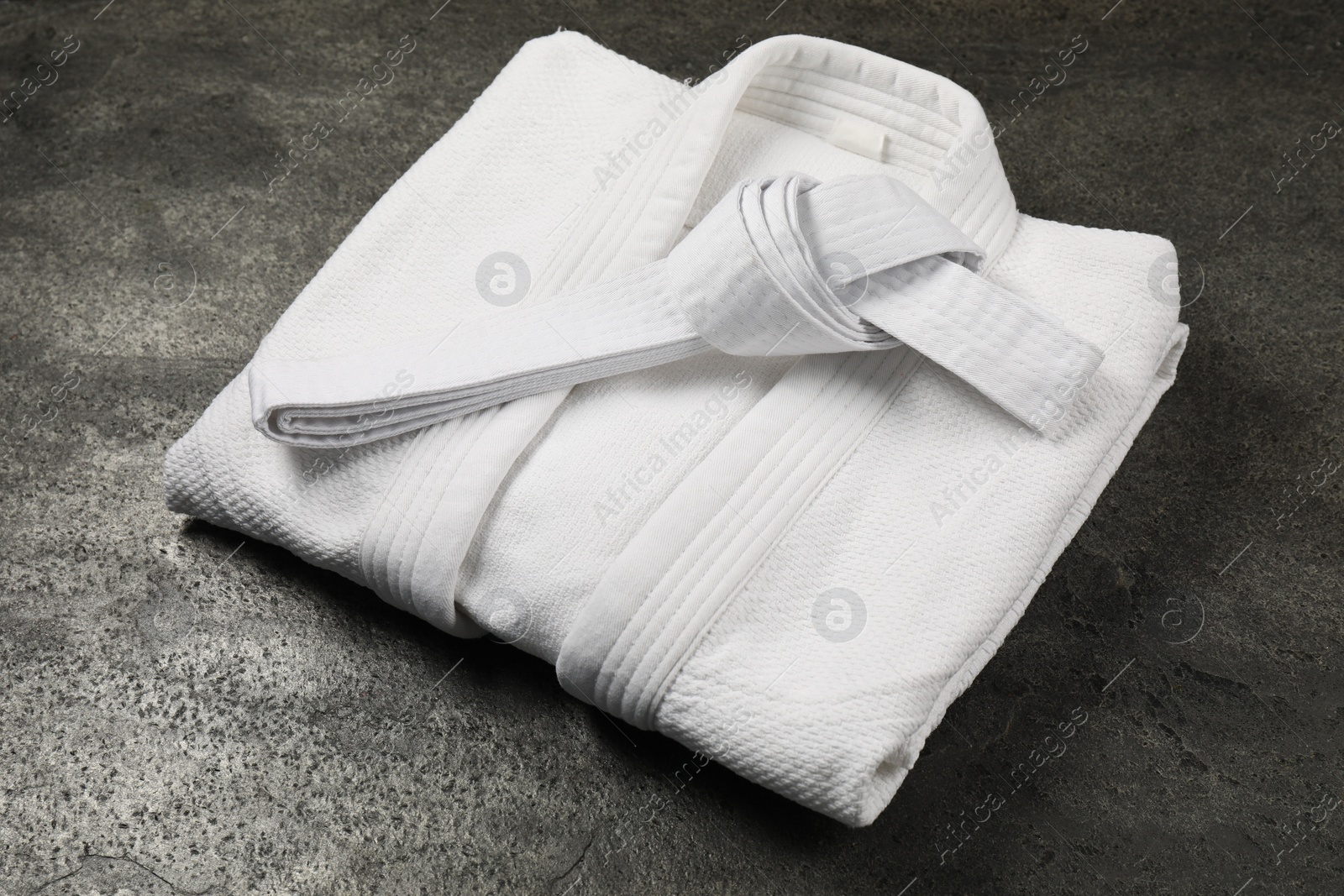 Photo of White karate belt and kimono on gray textured background