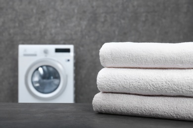 Stack of clean towels on table in laundry room, closeup. Space for text