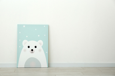 Photo of Adorable picture of bear on floor near white wall, space for text. Children's room interior element