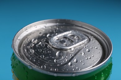 Photo of Energy drink in wet can on light blue background, closeup