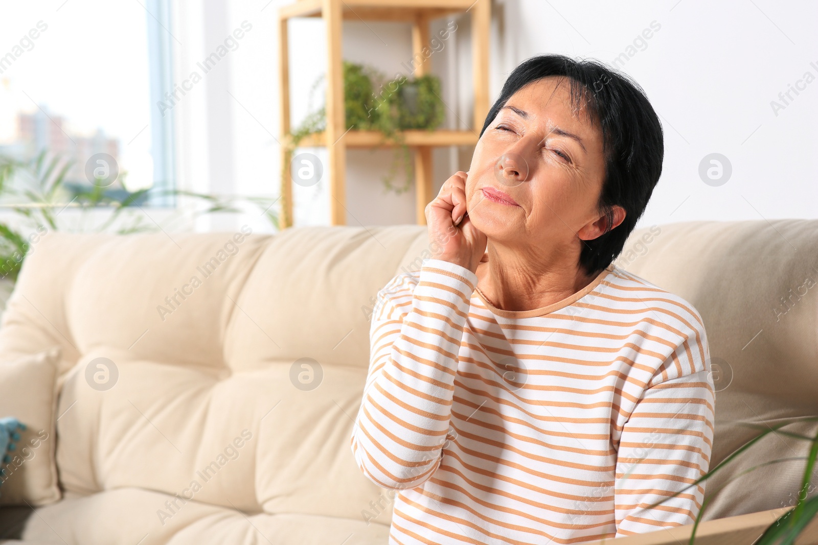 Photo of Senior woman suffering from ear pain at home. Space for text