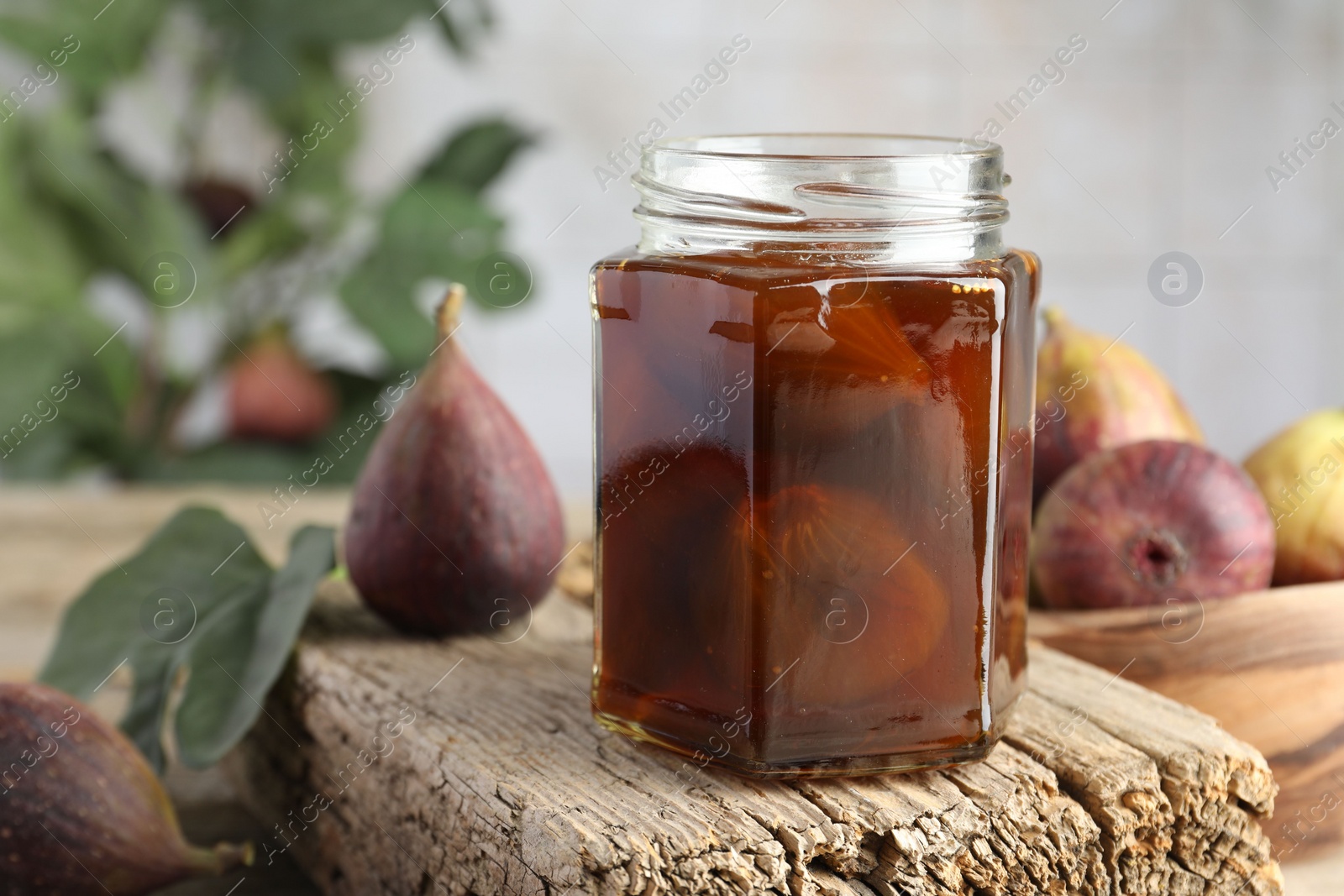 Photo of Jar of tasty sweet jam and fresh figs on wooden board