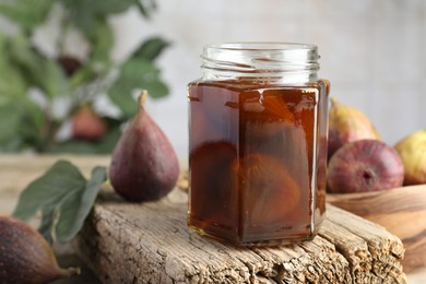 Jar of tasty sweet jam and fresh figs on wooden board