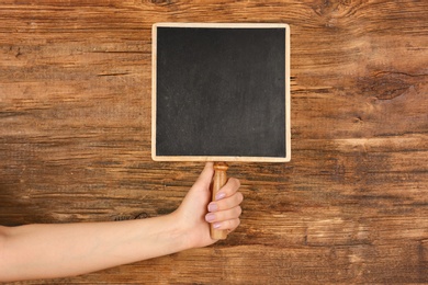 Woman holding small chalkboard on wooden background