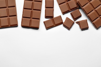 Pieces of delicious chocolate bar on white background, flat lay. Space for text