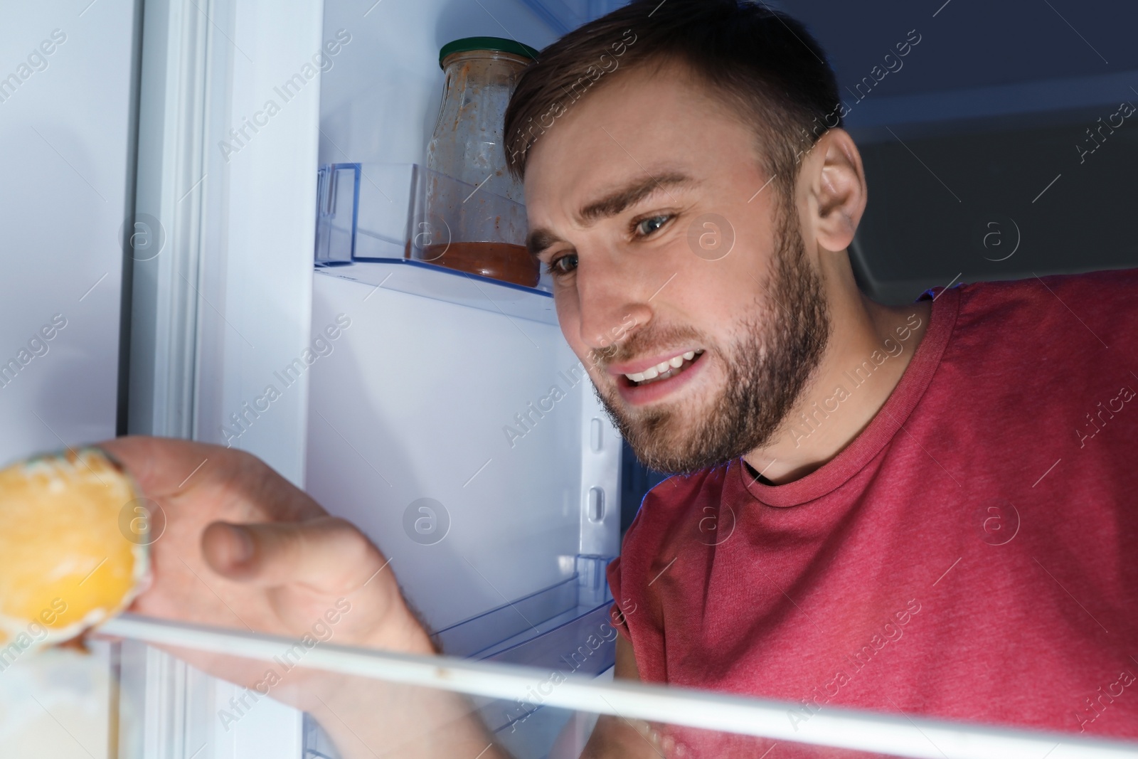 Photo of Man smelling stinky stale cheese in refrigerator