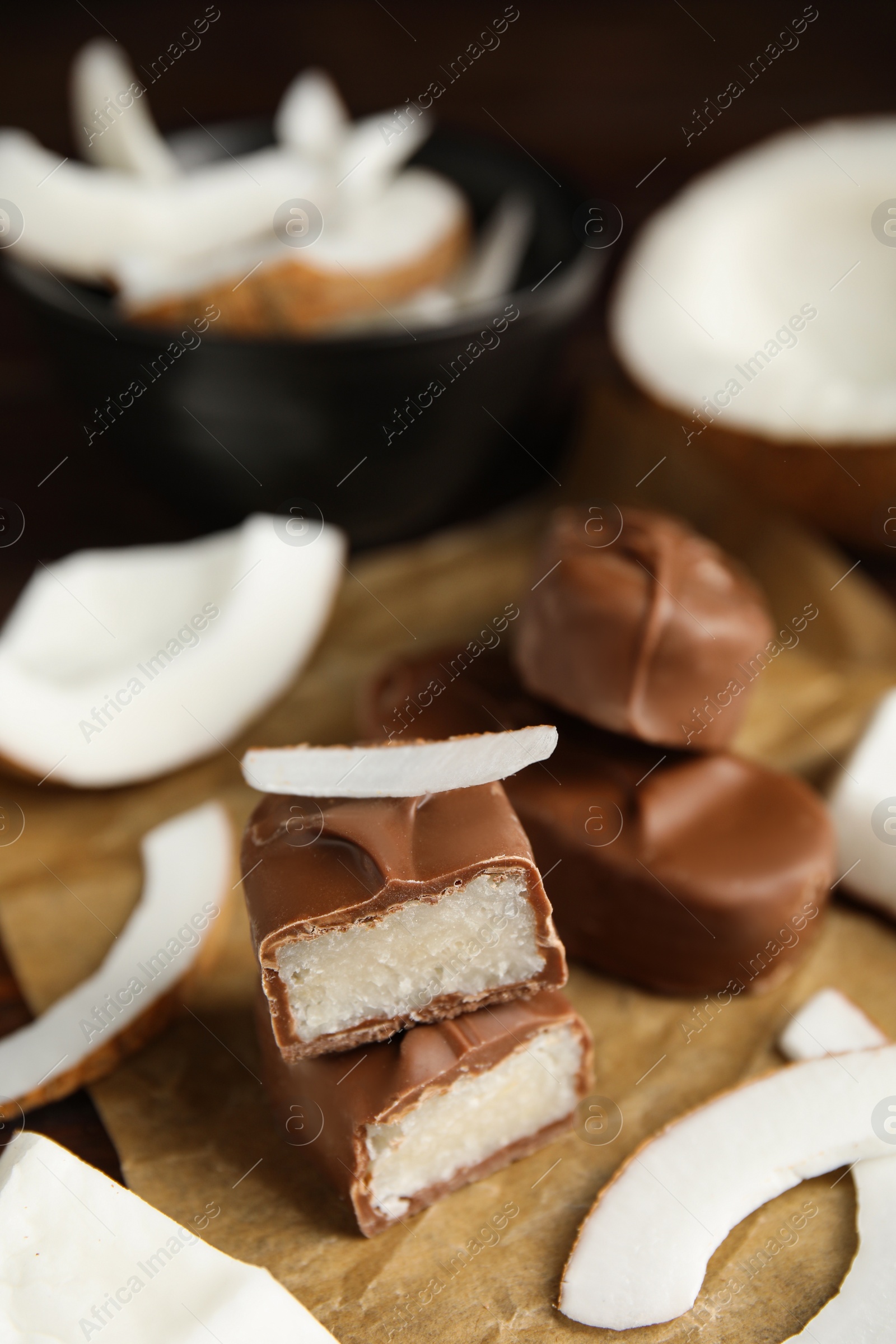 Photo of Delicious milk chocolate candy bars with coconut filling on table, closeup. Space for text