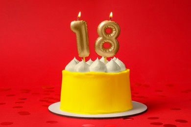 Photo of 18th birthday. Delicious cake with number shaped candles for coming of age party on red background